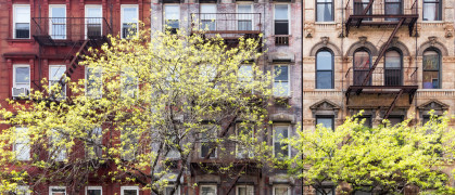 a row of new york city apartments with trees in front.